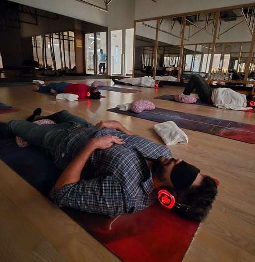 Founders from BonBillo's India & Southeast Asia cohort lying on yoga mats with bolsters, blankets and headphones during a breathwork workshop in a dimly lit, mirrored studio in Mumbai hosted by Neha Swaminathan