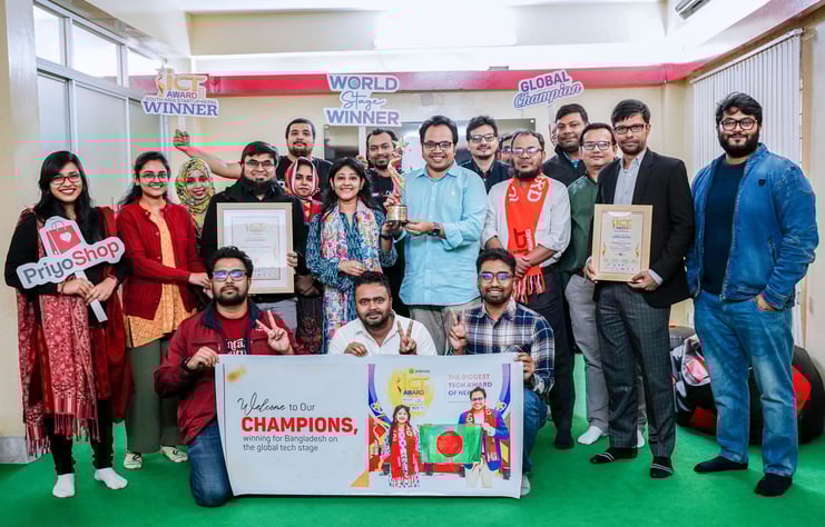 Team photo of PriyoShop employees holding their championship award and banner from the South Asia ICT Award 2025, demonstrating their recognition for pioneering micro-retail solutions in Bangladesh.