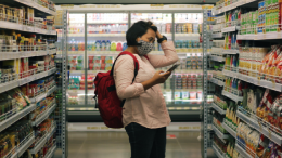 Image of a woman shopping in grocery aisle using greenchoice's app to make healthier choice.